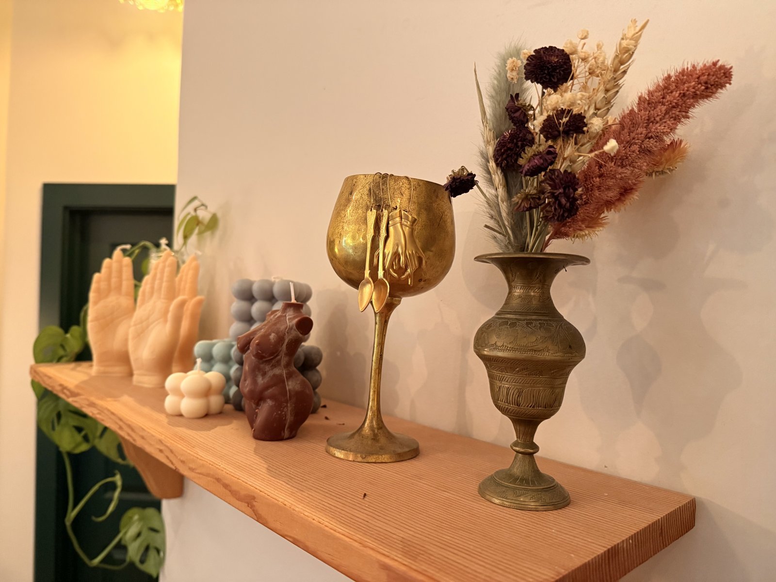 Treat salon shelf detail — candles, brass vase, dried florals